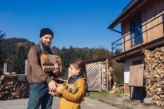 Figlia e papà tengono la legna da ardere tritata in cortile in autunno.