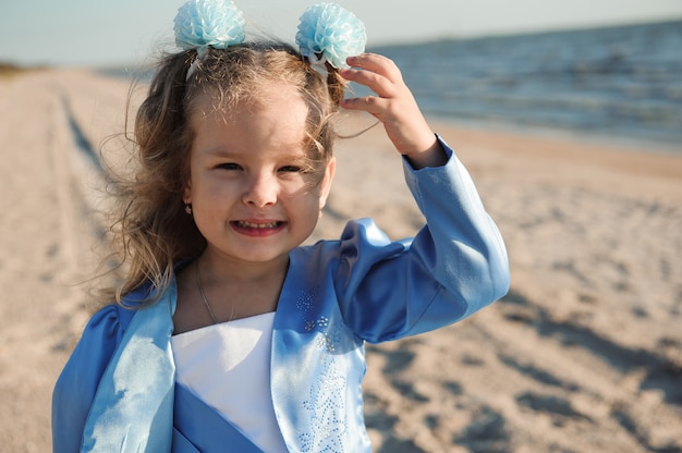 Figlia felice sulla spiaggia in un vestito blu