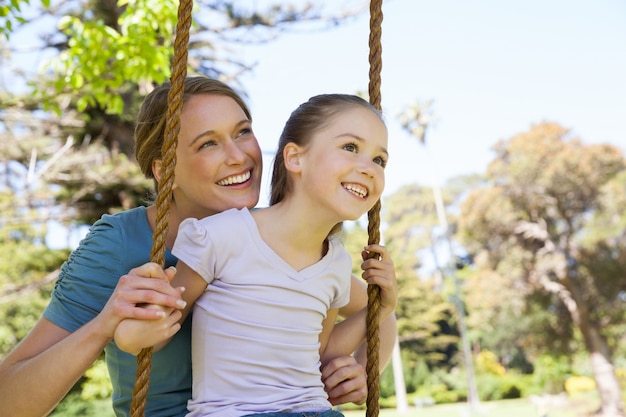 Figlia oscillante della madre felice al parco