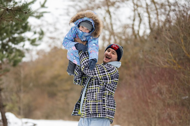 Figlia su un giro sulle spalle con suo padre nella foresta invernale