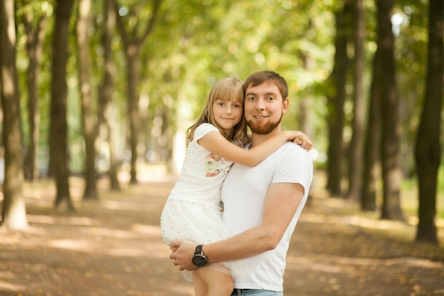 Figlia tra le braccia di suo padre al parco estivo.