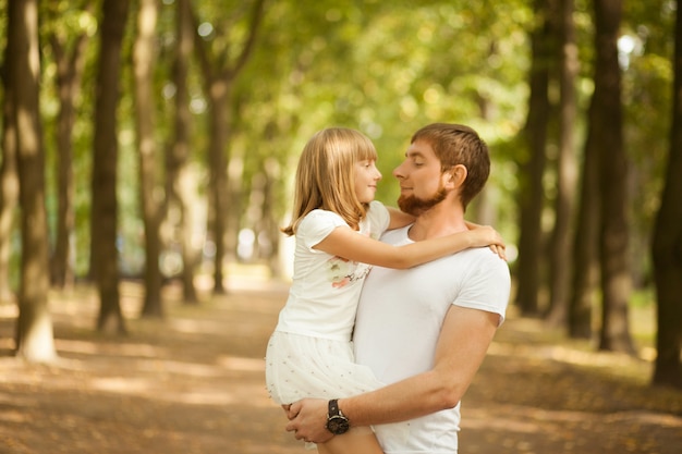 Figlia tra le braccia di suo padre al parco estivo.