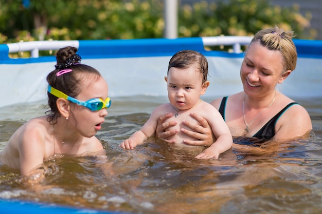 Figlie e famiglia madre che nuotano in piscina durante le vacanze estive