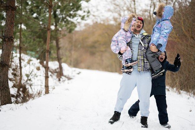 Figlie sulle mani di papà nella foresta invernale