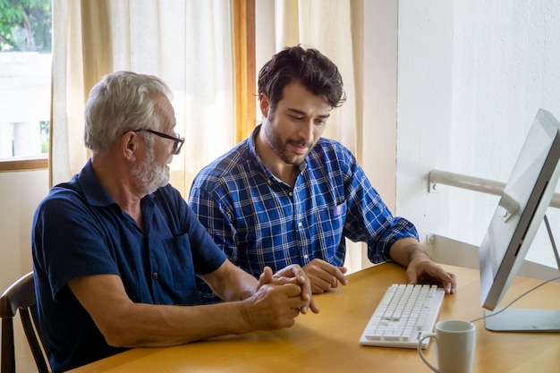 Figlio adulto che insegna al padre anziano all'utilizzo del computer