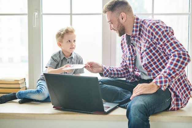 Figlio carino che dà la carta del giorno di padri a papà