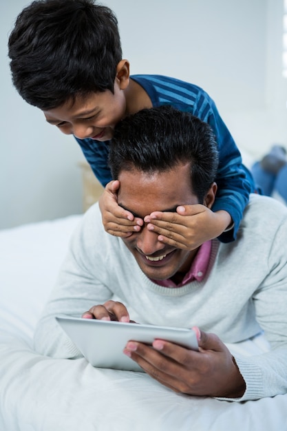 Figlio che copre gli occhi dei padri da dietro sul letto