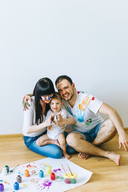 figlio di famiglia felice con i genitori dipingendo un poster