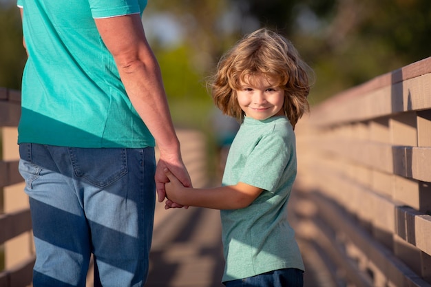 Figlio felice che allunga le mani padre bell'uomo e ragazzo carino all'aperto