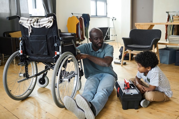 Figlio piccolo che aiuta il suo papà disabile con la riparazione