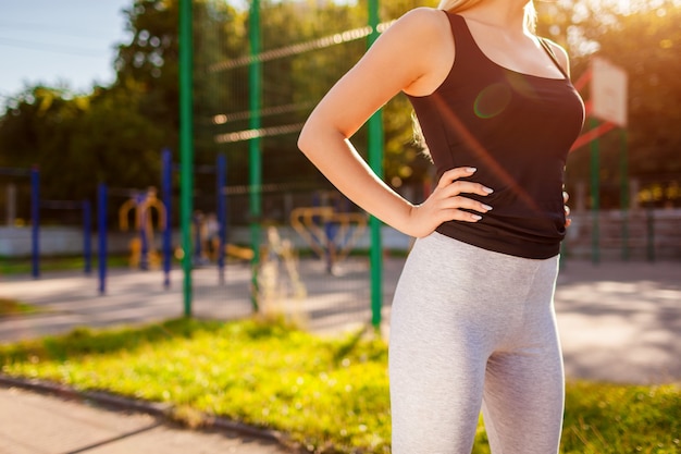 Figura di atleta di giovane donna in piedi sul campo sportivo in estate. Corpo snello sportivo. Stile di vita attivo