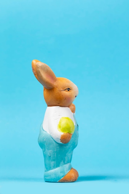 Figura di un coniglietto di Pasqua con un uovo su sfondo blu Carta di Pasqua