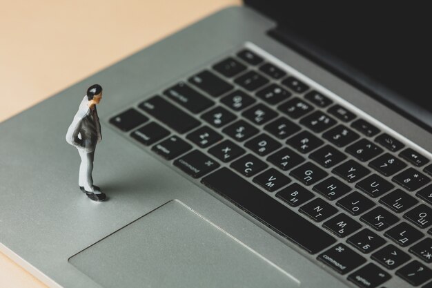 Figura in miniatura di un uomo d'affari sul computer portatile laptop