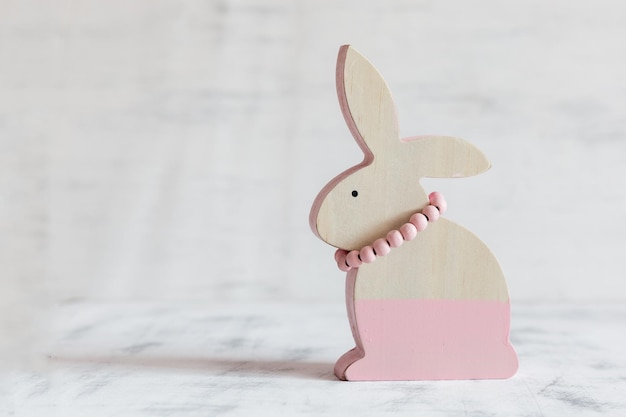 Figura rosa del coniglio di Pasqua in legno su sfondo bianco vintage Cartolina di Pasqua Copia spazio