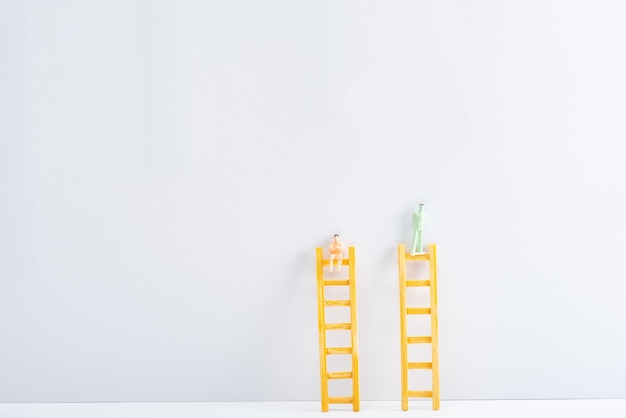 Figure di persone in plastica su scale su superficie bianca su sfondo grigio concetto di diritti di uguaglianza