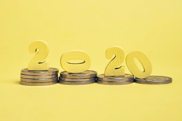 Figure in legno 2020 su pile di monete. Il concetto di stabilità finanziaria nel nuovo anno.