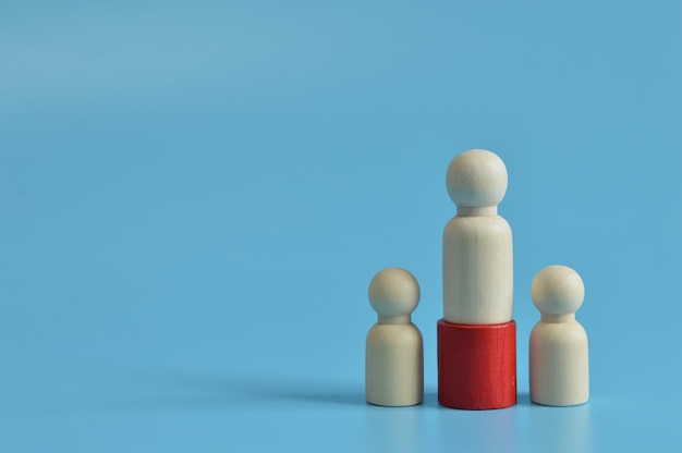 Figure in legno di persone isolate su sfondo blu Il concetto di vittoria e concorrenza tra imprese