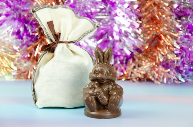 Figurina di cioccolato di coniglietto con borsa di regali su sfondo lucido sfocato lepre di cioccolato con regalo