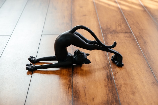 Figurina di gatto nero in ceramica che si piega facendo posa yoga