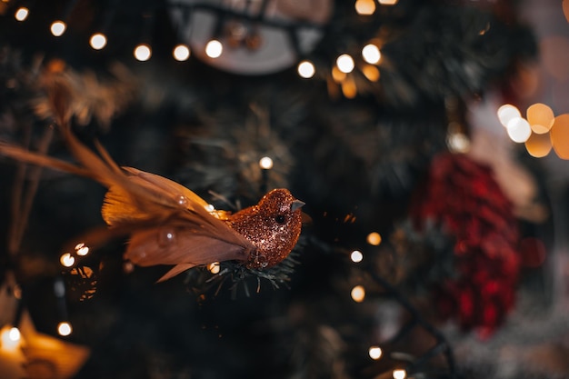 Figurina di Natale uccellino dorato appeso all'albero di Natale Dettagli magici con bokeh dorato
