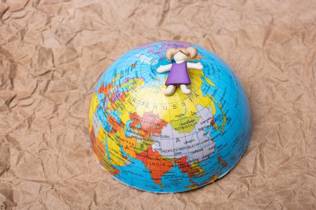 Figurina di ragazza in cima al globo come concetto di istruzione e business