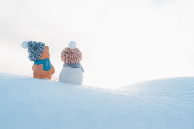 Figurina di statuetta di cartolina di Natale di due pupazzi di neve berretto su uno sfondo innevato all'aperto