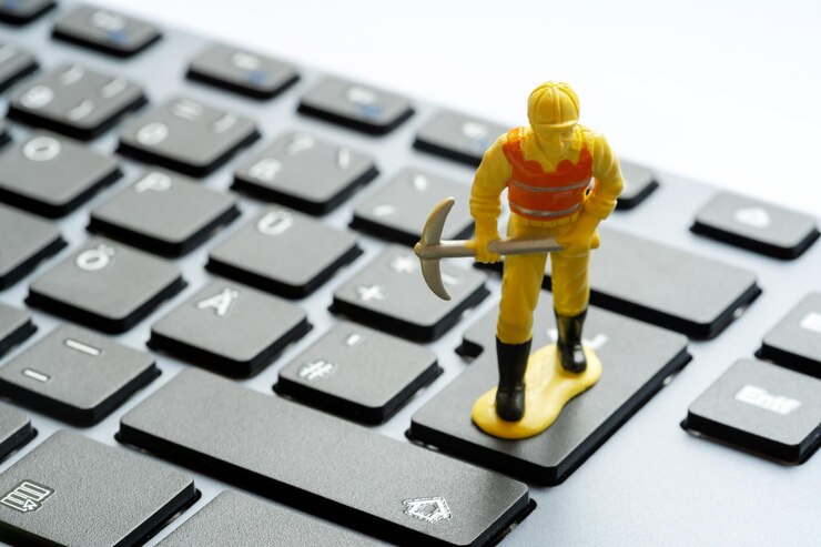 Figurina di un operaio edile con un piccone in piedi sulla parte superiore di una semplice tastiera di un computer desktop Data mining cryptocurrency mining IT service hardware repair and fixes abstract concept