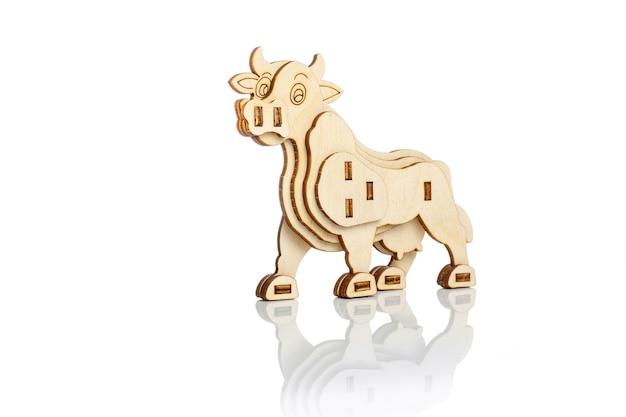 Figurina di una mucca di legno giocattolo su uno sfondo bianco con la riflessione.