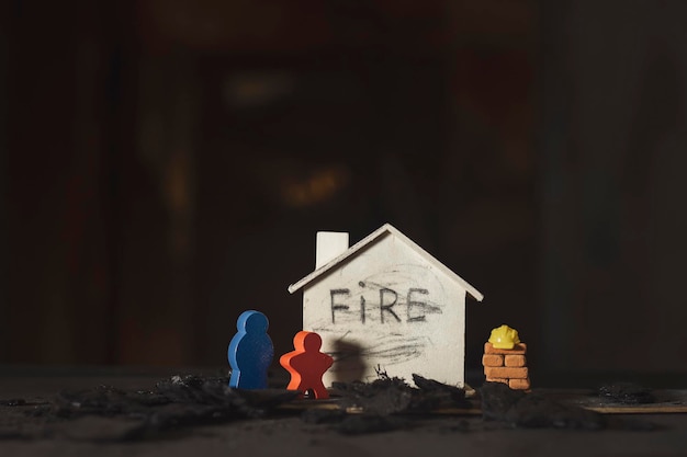 Figurine in legno casa in legno mattoni rossi con le conseguenze del fuoco domestico sullo sfondo