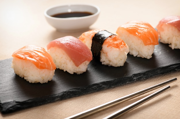 Fila dei sushi freschi di nighiri su un vassoio nero
