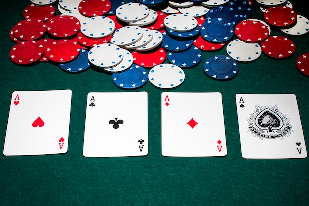 Fila di assi e fiches del casinò sul tavolo da poker verde