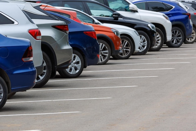 Fila di auto di colore diverso sul parcheggio in asfalto in una giornata estiva nuvolosa