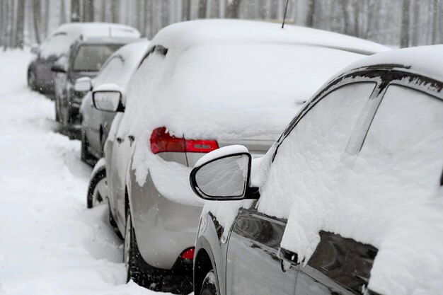 Fila di auto parcheggiate coperte di neve Parcheggio innevato nella strada della città