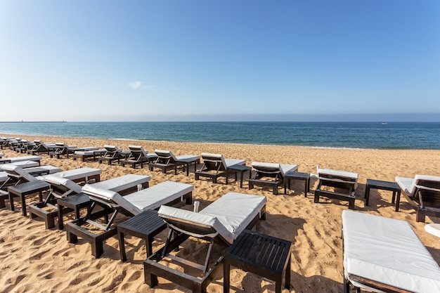 Fila di lettini per prendere il sole in primo piano sulla spiaggia in Algarve.