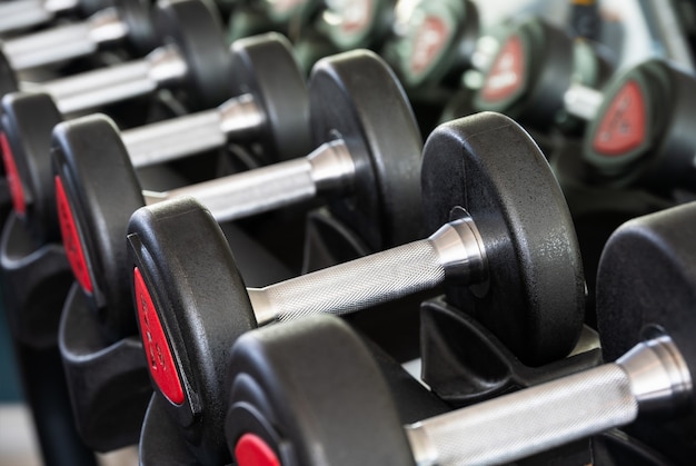 Fila di manubri in metallo su rack nel club sportivo per allenamento con i pesi weight