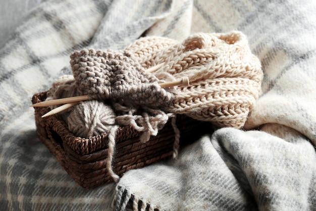 Filati per maglieria e aghi in cesto di vimini su plaid