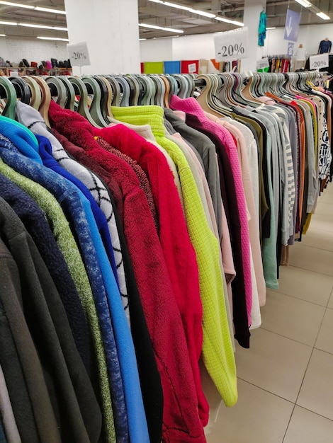 File di appendiabiti con una varietà di abiti colorati e camicie in un negozio di abbigliamento in prospettiva