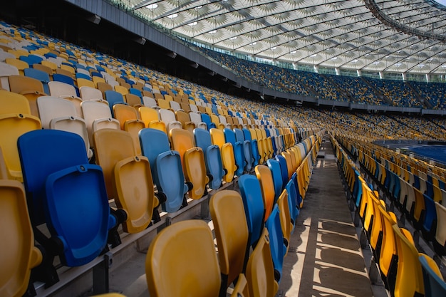 File vuote di sedili in uno stadio olimpico di calcio con panchine gialle e blu