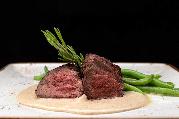 Filet mignon con asparagi su piatto chiaro su fondo scuro