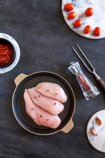 Filetti di petto di pollo crudi con pomodori, ketchup e spezie.