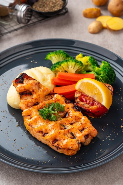 Filetti di salmone alla griglia con salsa mentai e purè di patate su piastra nera con spazio negativo