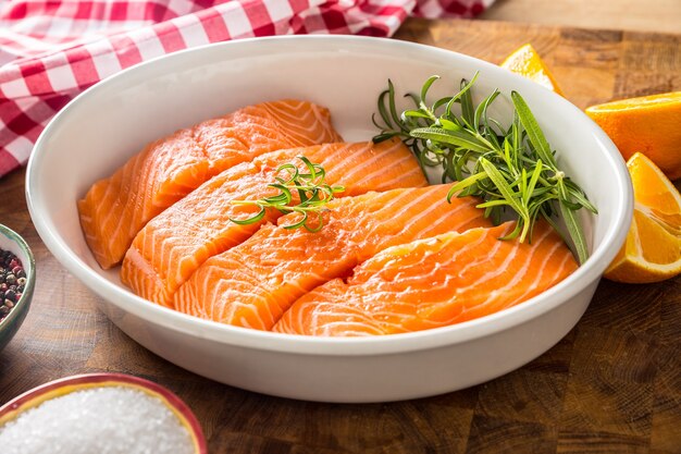 Filetti di salmone crudo con erbe aromatiche in una teglia.