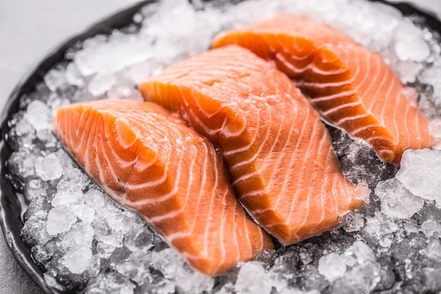 Filetti di salmone crudo porzionati in ghiaccio sul piatto - primo piano.