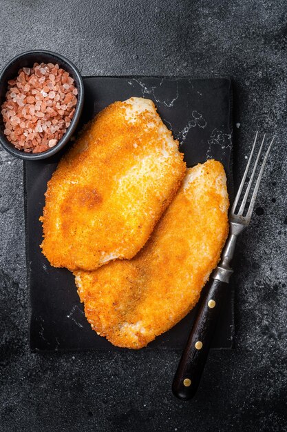 Filetti di tilapia impanati fritti su una tavola di marmo Sfondo nero Vista dall'alto