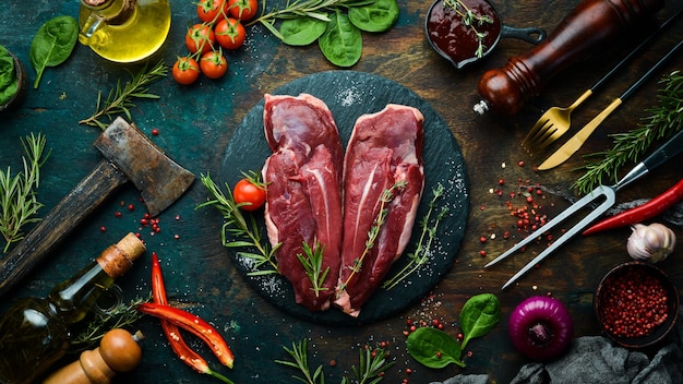 Filetto d'anatra fresco crudo con rosmarino e spezie su sfondo nero Vista dall'alto