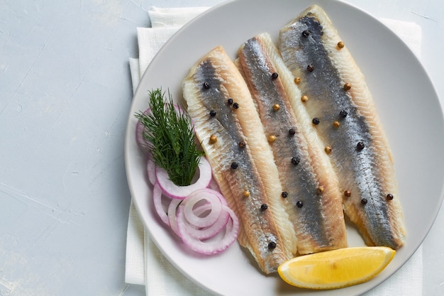 Filetto di aringa salato decorato con aneto pepe limone cipolla rossa