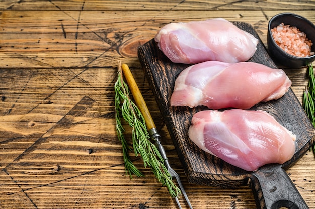 Filetto di coscia di pollo crudo disossato. Fondo in legno. Vista dall'alto. Copia spazio.