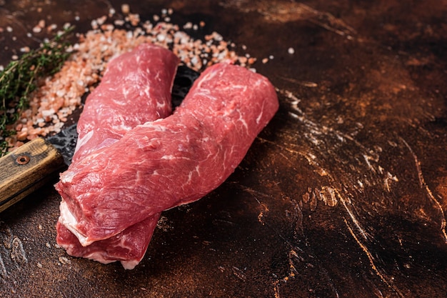 Filetto di lombo di agnello crudo Carne di montone cruda su mannaia da macellaio Sfondo scuro Vista dall'alto Copia spazio