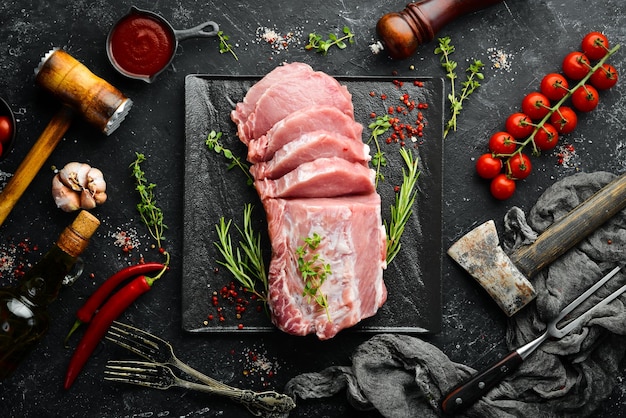 Filetto di maiale crudo con spezie su fondo di pietra nera Carne Vista dall'alto Stile rustico