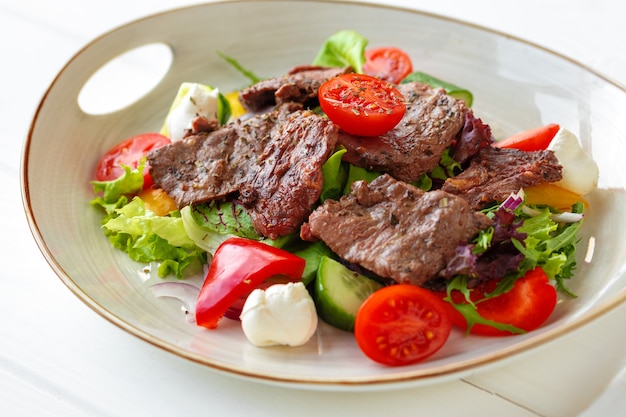 Filetto di manzo con insalata di verdure su tavola di legno